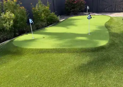 High-quality artificial turf for golf practice, surrounded by lush plants and a privacy fence.